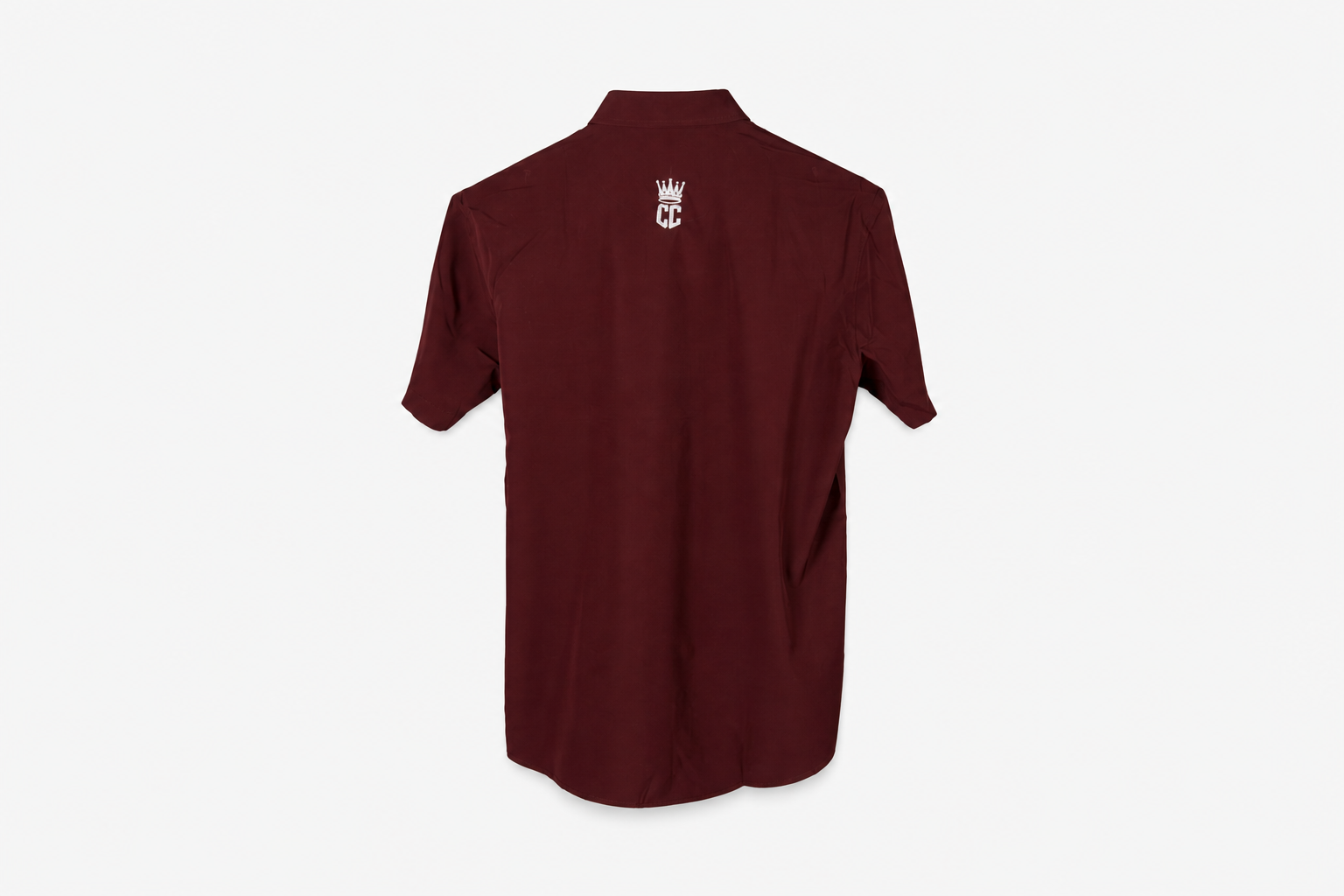 A maroon short-sleeve button-up shirt with a small white crown and 'M' logo on the left chest, displayed on a clean white background.